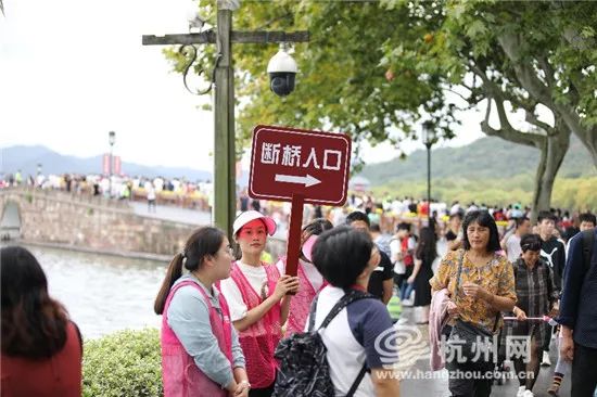 国庆首日，西湖游客悠然雨中行！有游客断桥上用手机看起“大阅兵”