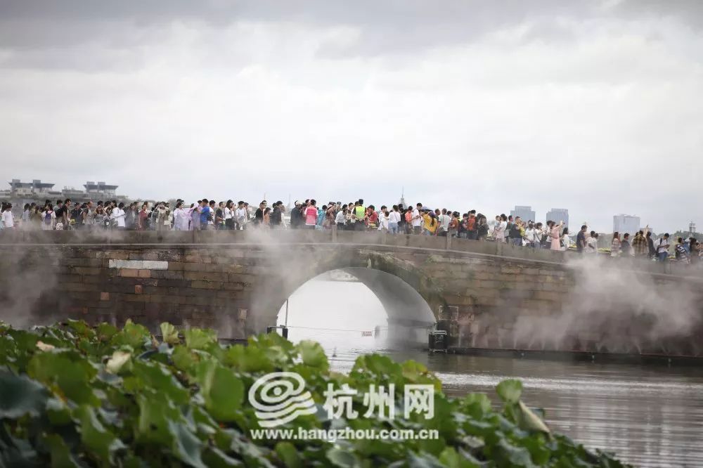 国庆首日，西湖游客悠然雨中行！有游客断桥上用手机看起“大阅兵”