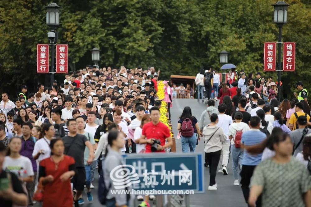 国庆首日，西湖游客悠然雨中行！有游客断桥上用手机看起“大阅兵”